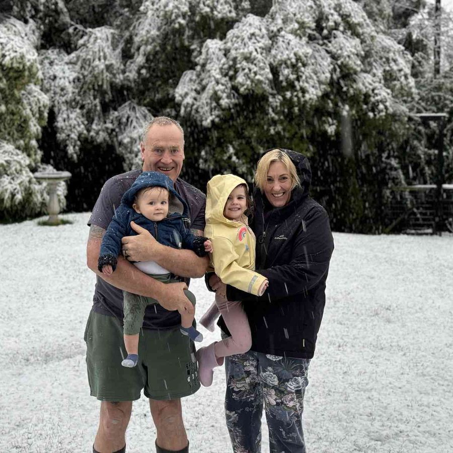 Jen and her husband holding the grandchildren in a snowy garden