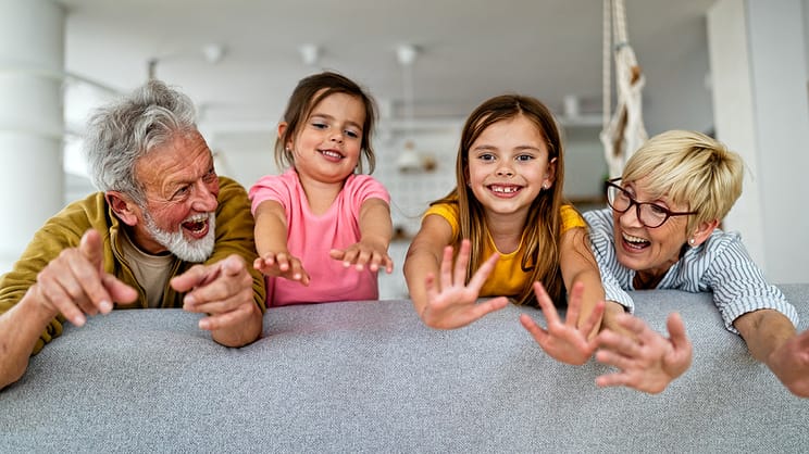 Grandparents laughing on the couch with two grandchildren